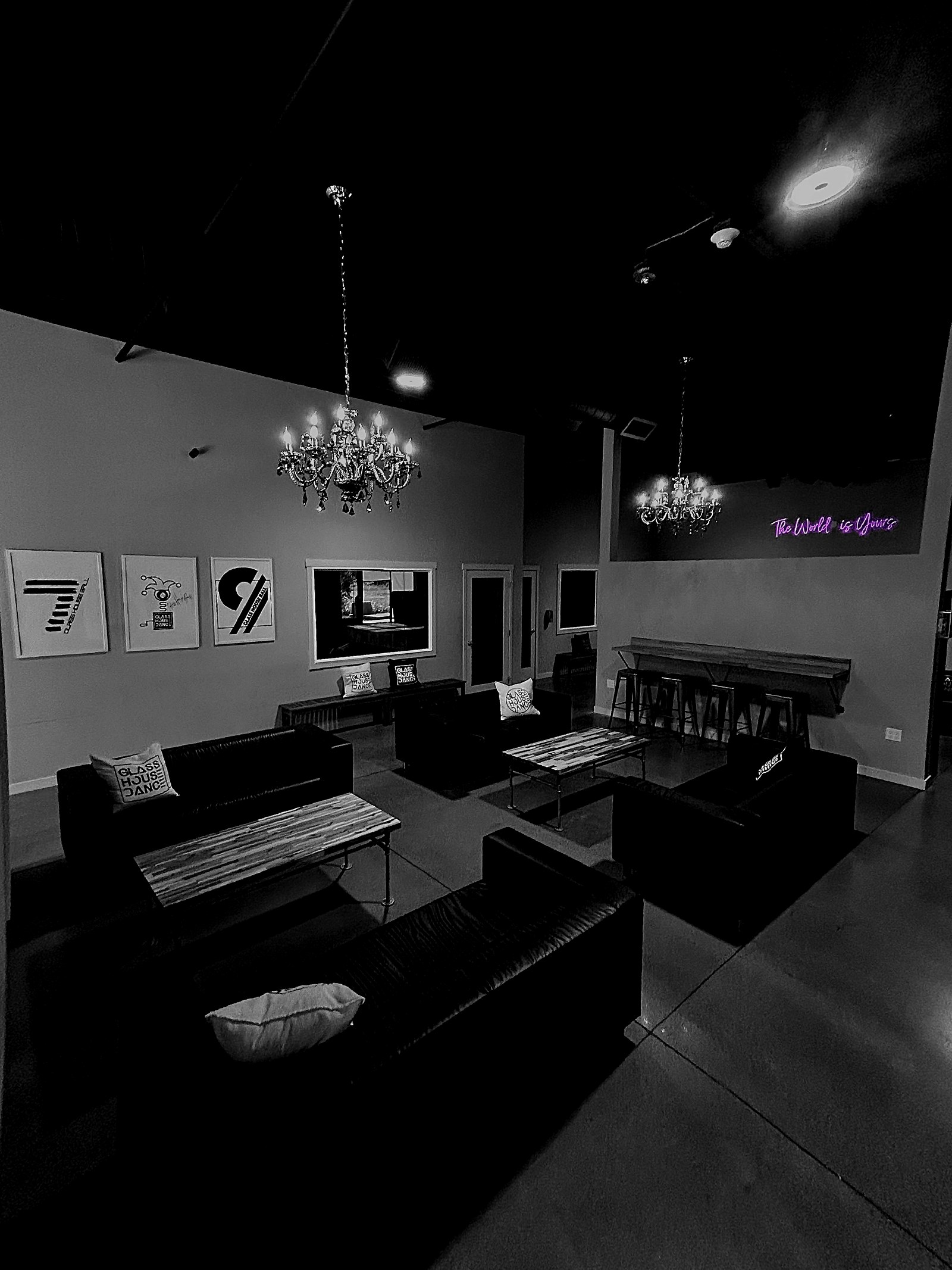 The lounge at Glass House Dance, Black Diamond campus — chandeliers, seating and the neon sign reading The World Is Yours